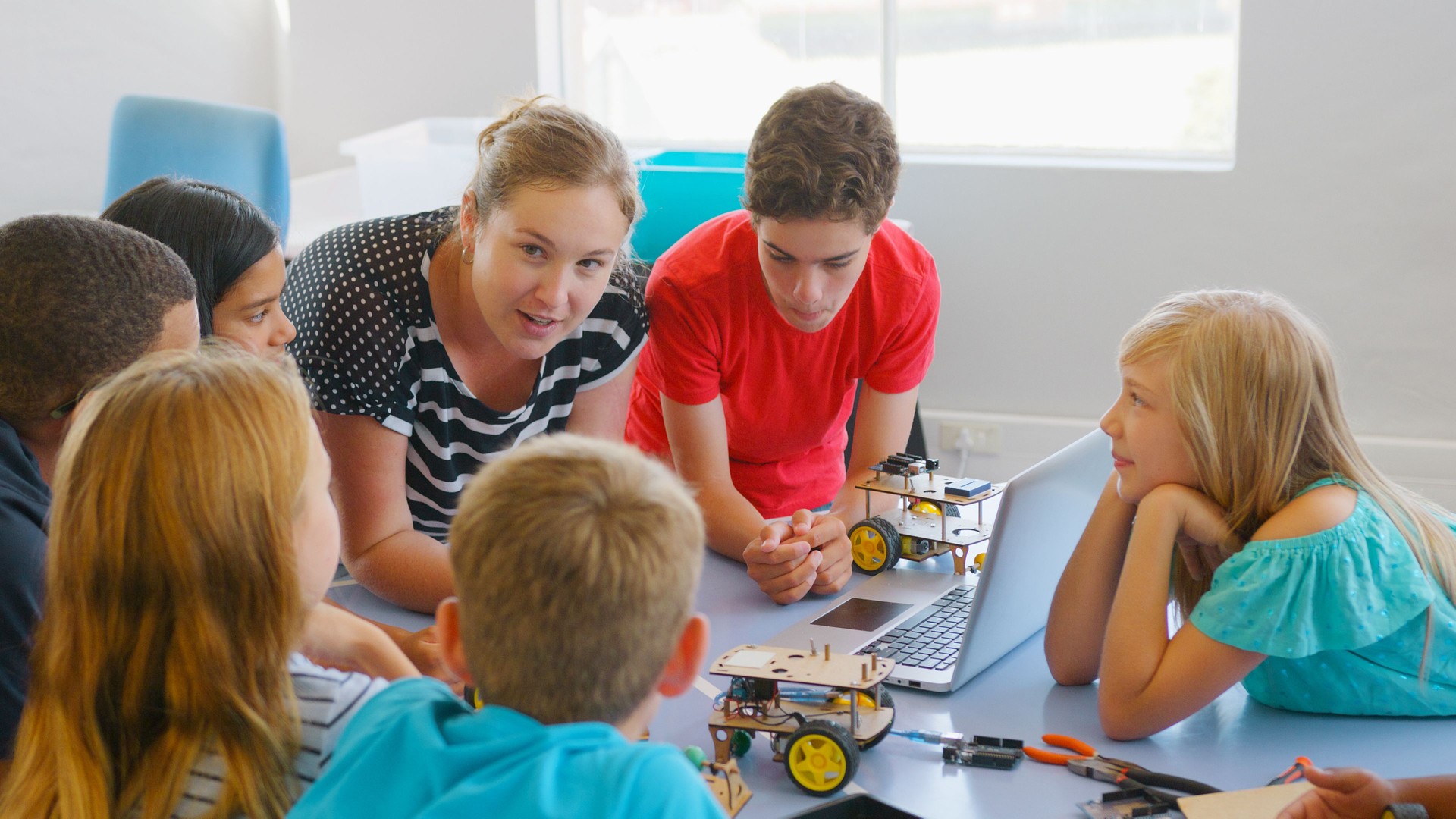 Group Of Students With Female Teacher In School Computer Coding Class Learn To Program Robot Vehicle